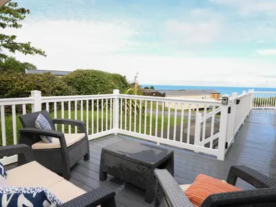 a deck with chairs and tables and the ocean at The Potting Shed in New Quay
