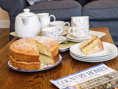 a table with a cake and cups and a book at The Cider House in Leominster