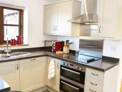 a kitchen with white cabinets and a stove top oven at The Cider House in Leominster