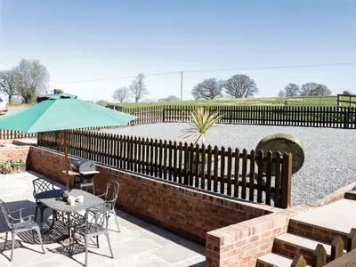a patio with a table and chairs and an umbrella at The Cider House in Leominster