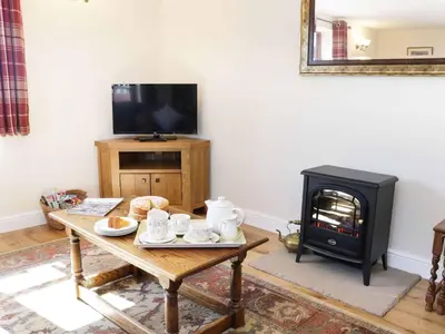 a living room with a table and a stove at The Cider House in Leominster