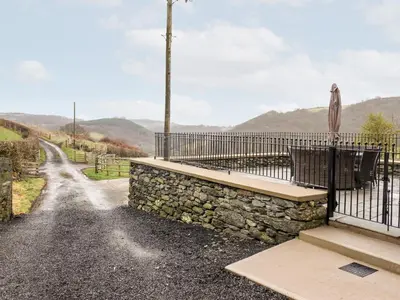 a bench on a stone wall next to a fence at Hen Dy Bryn Mawndy in Corwen