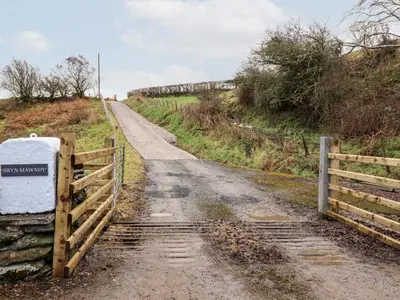 a dirt road with a fence on the side at Hen Dy Bryn Mawndy in Corwen