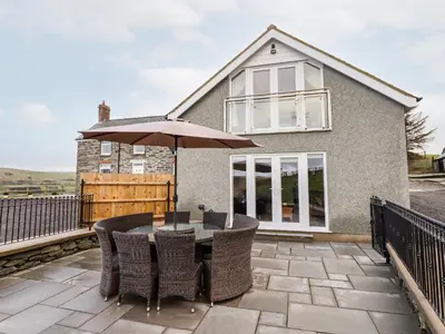 a patio with a table and an umbrella at Hen Dy Bryn Mawndy in Corwen