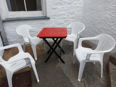 four white chairs and a table with a red tabletop at 52 Cambrian St in Aberystwyth