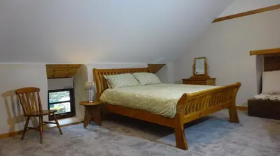a bedroom with a bed and a chair and a window at Blaentwrch Farmhouse in Llanddewi-Brefi