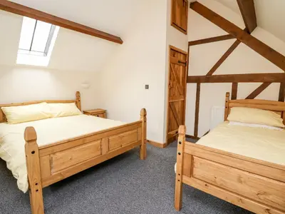 two twin beds in a room with wooden beams at Ploony Barn in Bleddfa