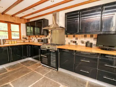 a kitchen with black cabinets and a stove at Ploony Barn in Bleddfa