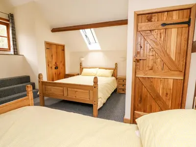 a bedroom with two beds and a sliding barn door at Ploony Barn in Bleddfa