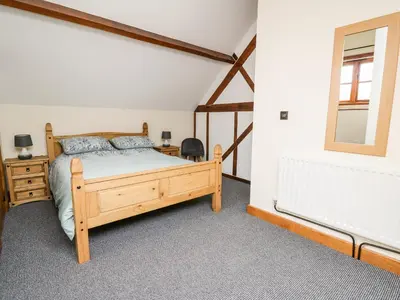 a bedroom with a wooden bed and a window at Ploony Barn in Bleddfa