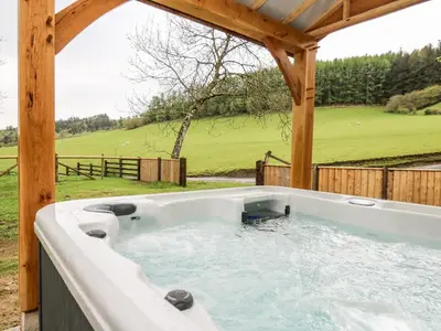 a hot tub in a gazebo with a view at Ploony Barn in Bleddfa
