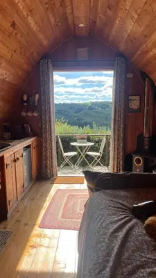 a bedroom with a large window with a view of a table at Hillside hideaway - Hendre-Aur Pod in Machynlleth