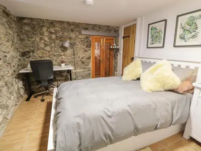 a bedroom with a bed with a stone wall at Brithgwm Canol in Dolgellau