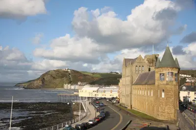 a building on a road next to the ocean at Fferm Penglais Apartments in Aberystwyth