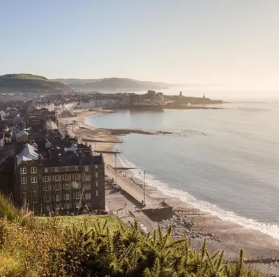 a view of a beach with buildings and the ocean at Fferm Penglais Apartments in Aberystwyth