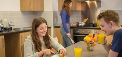 a man and woman sitting at a table in a kitchen at Fferm Penglais Apartments in Aberystwyth