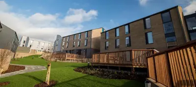 a building with a green lawn in front of it at Fferm Penglais Apartments in Aberystwyth