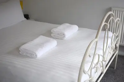 a white bed with two folded towels on it at 2 bed house, walking distance Shrewsbury centre in Shrewsbury