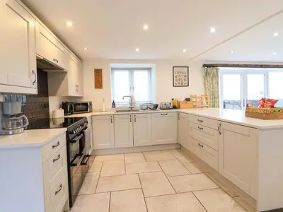 a large kitchen with white cabinets and white appliances at Bwthyn Y Bugail Shepherd's Cottage in Oswestry