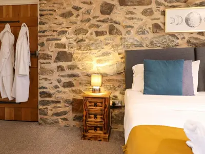 a bedroom with a bed and a stone wall at Bwthyn Y Bugail Shepherd's Cottage in Oswestry
