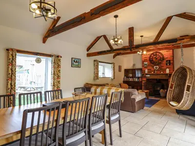 a dining room and living room with a table and chairs at Y Beudy The Dairy in Oswestry