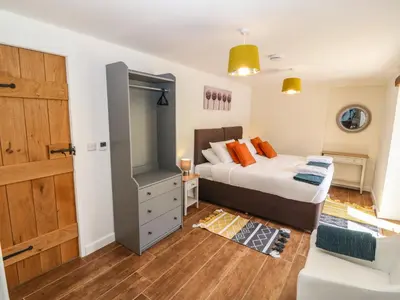 a bedroom with a bed and a wooden door at Y Beudy The Dairy in Oswestry