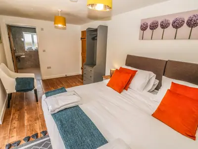 a bedroom with a large white bed with orange pillows at Y Beudy The Dairy in Oswestry