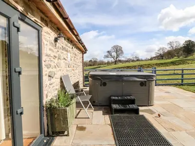 a hot tub on the patio of a house at Y Beudy The Dairy in Oswestry