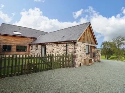 a stone house with a fence in front of it at Y Granar The Granary in Oswestry