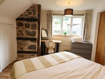 a bedroom with a bed and a stone wall at Y Granar The Granary in Oswestry