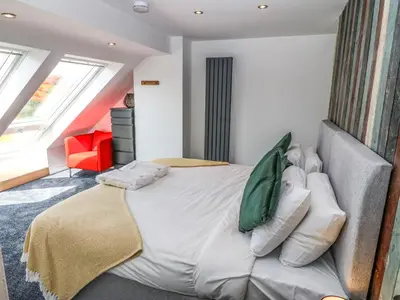 a bedroom with a large bed and a red chair at Y Granar The Granary in Oswestry