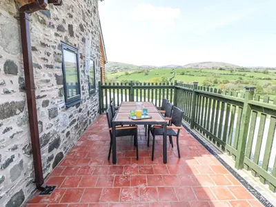 a patio with a table and chairs on a balcony at Y Granar The Granary in Oswestry