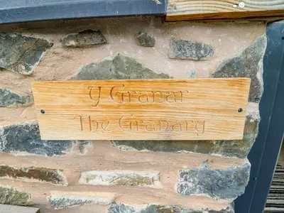 a wooden sign on the side of a stone wall at Y Granar The Granary in Oswestry