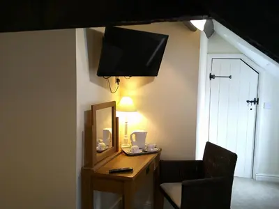 a room with a desk with a mirror and a chair at The Crown Hotel in Corwen