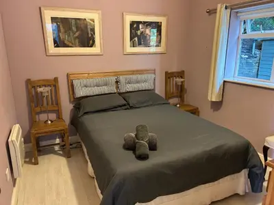 a bedroom with a bed with a teddy bear on it at Milkwood Cottage in Corwen
