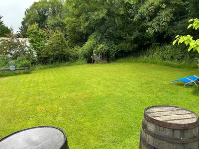 a lawn with a barrel in the middle of a yard at Milkwood Cottage in Corwen