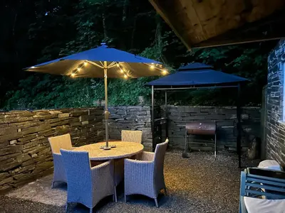 a table with chairs and an umbrella on a patio at Milkwood Cottage in Corwen