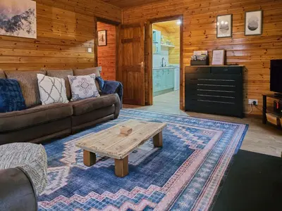a living room with a couch and a coffee table at Luxury Wood Lodge with sauna, log burner & private woodland garden - Wnion Wood Lodge in Llanfachreth