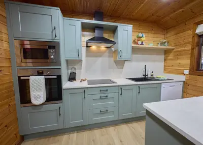 a kitchen with blue cabinets and a stove at Luxury Wood Lodge with sauna, log burner & private woodland garden - Wnion Wood Lodge in Llanfachreth