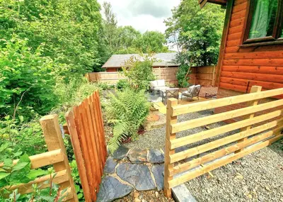 a wooden fence in front of a house at Luxury Wood Lodge with sauna, log burner & private woodland garden - Wnion Wood Lodge in Llanfachreth