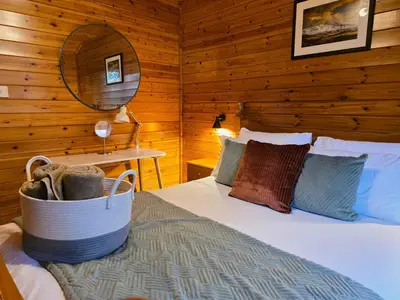 a bedroom with a bed in a log cabin at Luxury Wood Lodge with sauna, log burner & private woodland garden - Wnion Wood Lodge in Llanfachreth