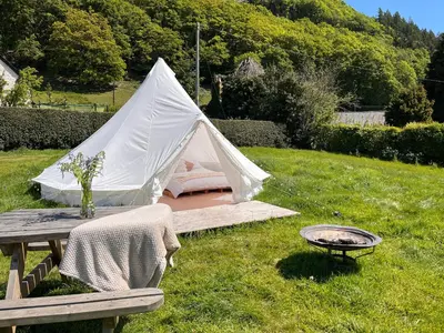 a tent in the grass with a table and a grill at Panpwnton Farm Bell Tents in Knighton