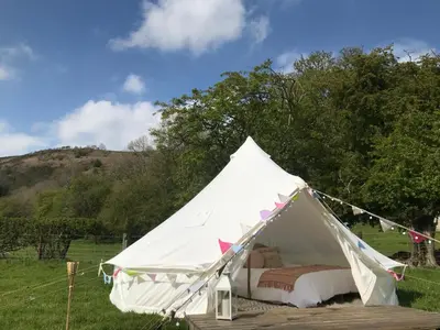 a white tent with a bed in a field at Panpwnton Farm Bell Tents in Knighton