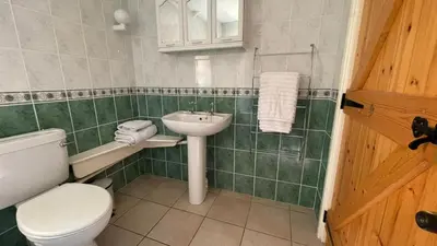 a green tiled bathroom with a toilet and a sink at Crug Yr Eryr Isaf in Llandysul