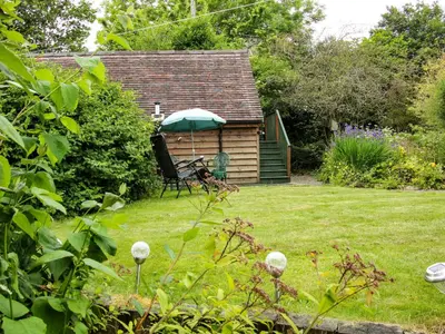 a garden with a bench and an umbrella at Milford Tree Tops in Craven Arms