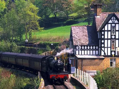 a steam train traveling past a house on the tracks at Fern Studio 1 Bedroom Apartment in Llangollen
