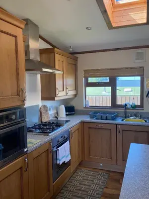 a kitchen with wooden cabinets and a stove top oven at The Oak Lodge in Aberystwyth