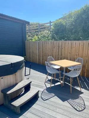 a wooden deck with a table and chairs and a fence at The Oak Lodge in Aberystwyth