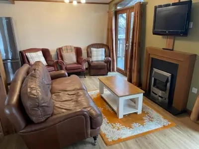 a living room with a leather couch and a fireplace at The Oak Lodge in Aberystwyth