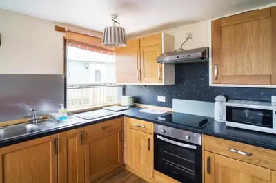 a kitchen with wooden cabinets and a sink and a microwave at The Pine Lodge in Aberystwyth